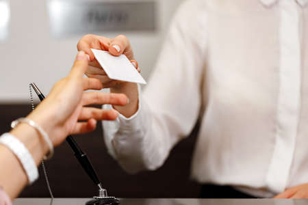 Woman receiving door key in hotel front deskの写真素材