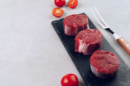 Raw veal medallions on black stone boardの写真素材