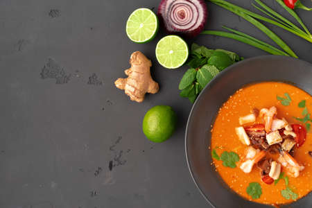 Tom yam Thai soup in black bowl served on gray backgroundの写真素材
