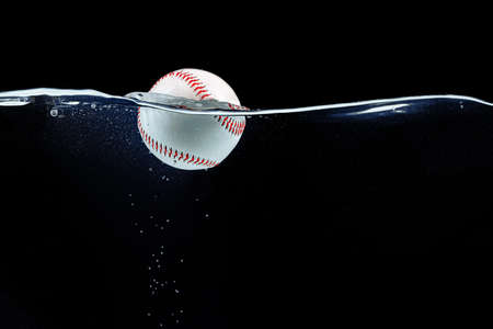 Baseball ball floating in the water against black backgroundの写真素材