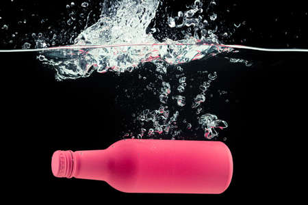 Painted bottle diving into the water with a splashの写真素材