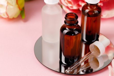 Glass bottle with oil on round mirror on pink backgroundの写真素材