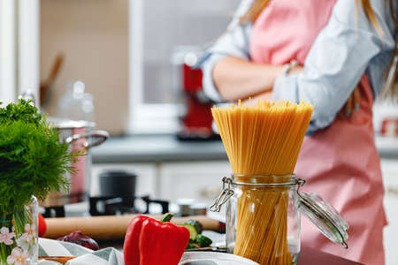 Unrecognizable woman cooking something near the stove in kitchen close upの写真素材