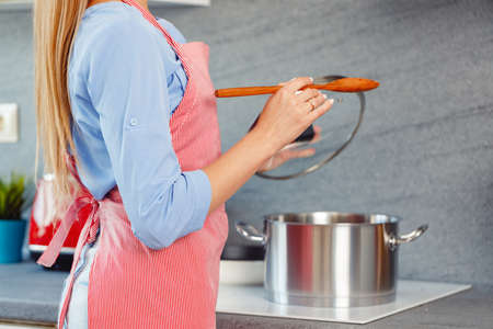Unrecognizable woman standing in her kitchen close up photoの写真素材