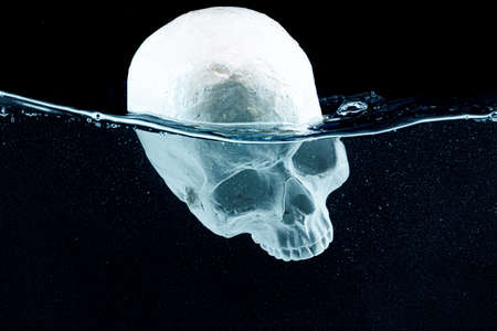 Skull model diving into the water against black backgroundの写真素材