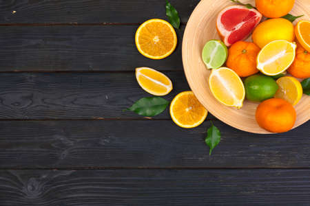 Bowl of citrus fruits on black wooden background, top viewの写真素材