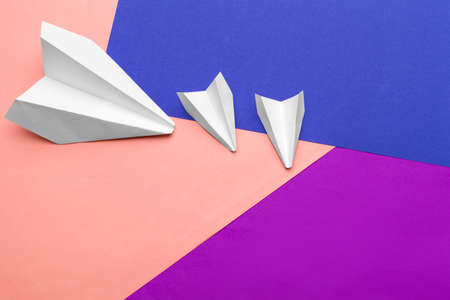 white paper airplane on a color block paper backgroundの写真素材