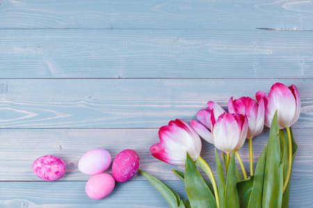Easter eggs with tulips on blue wooden background