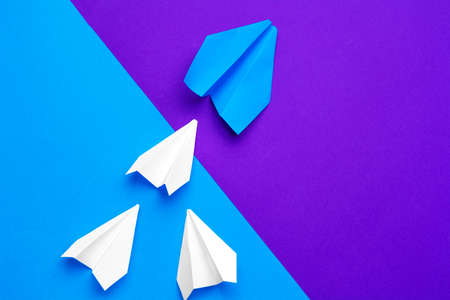 white paper airplane on a blue and purple paper backgroundの写真素材