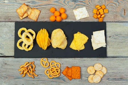 Mix of snacks : pretzels , crackers , chips and nachos on the tableの写真素材