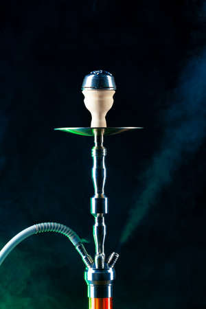 Modern hookah with smoke in dark club light