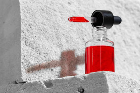 Glass jar of skincare serum on concrete block