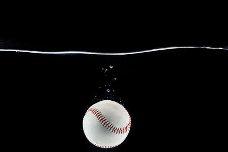 Baseball ball floating in the water against black backgroundの写真素材