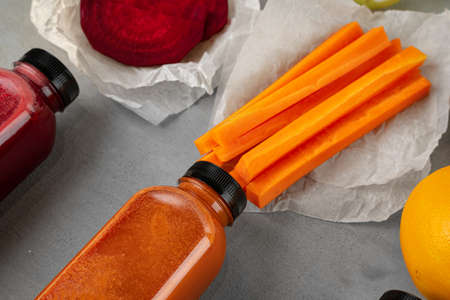 Fresh carrot juice in plastic bottle on gray backgroundの写真素材