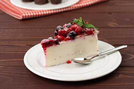 Piece of berry cheesecake served on brown wooden table