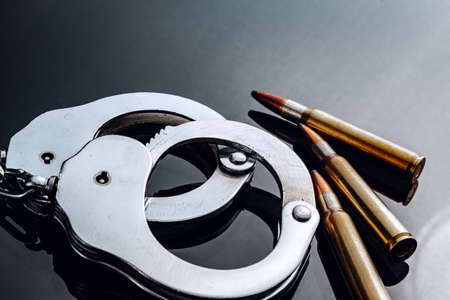 Handcuffs and rifle bullets on black backgroundの写真素材