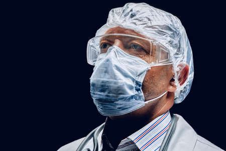 Male doctor wearing protective Mask and Goggles. Dark background.の写真素材