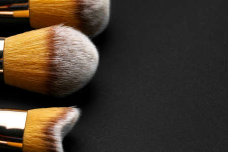 Collection of make up brushes on black background