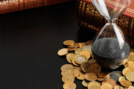 Time is money. Close up of hourglass with money coins