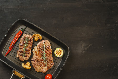 Beef steaks with vegetables on grill panの写真素材