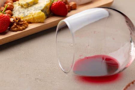 Glass of wine and piece of cheese on table close up