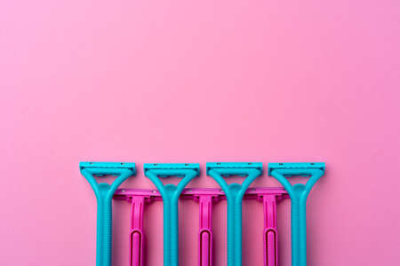 Female disposable razors on pink background top view
