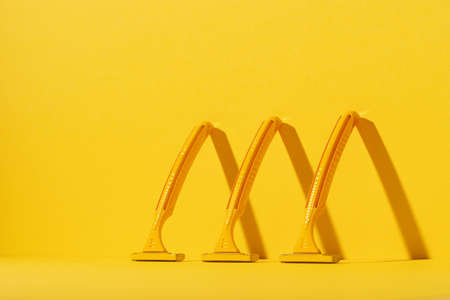 Disposable razors on yellow background, studio shot