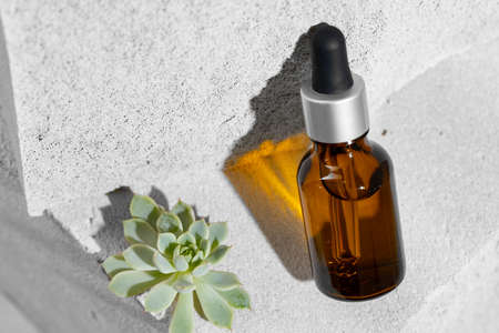 Glass jar of skincare serum on concrete blockの写真素材