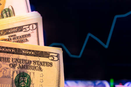 American dollar banknotes and graph on black background