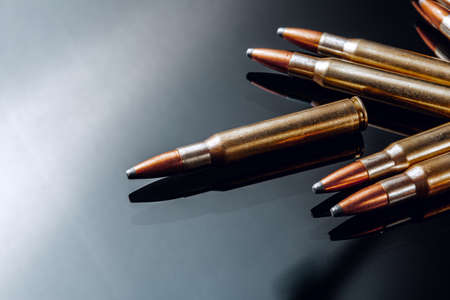Rifle bullets or cartridges on black shiny background