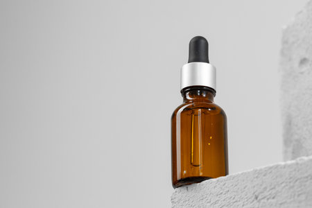 Glass jar of skincare serum on concrete blockの写真素材