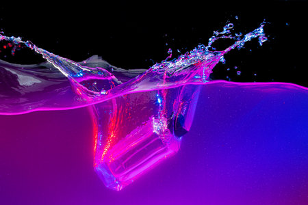 Perfume bottle diving into the water with a splash in neon light