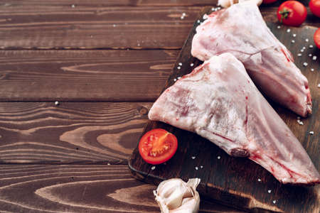 Raw lamb leg on dark wooden boardの写真素材