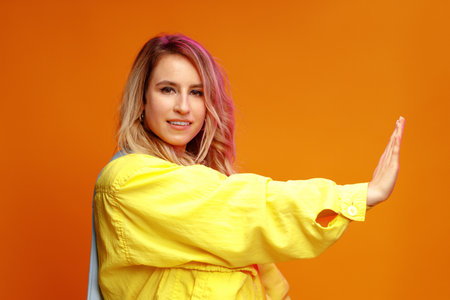 Trendy fashionable woman dancer posing against yellow backgorund