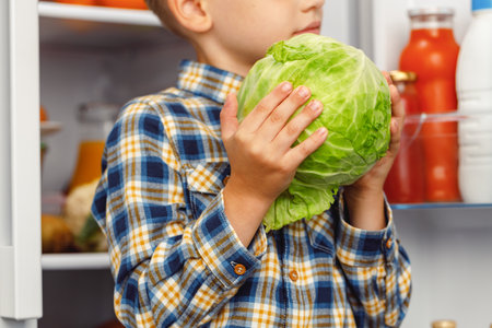 Little boy standing near the open fridgeの写真素材