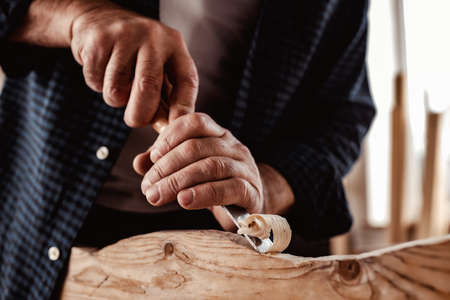 Hands of a carpenter working with chisel and hammer