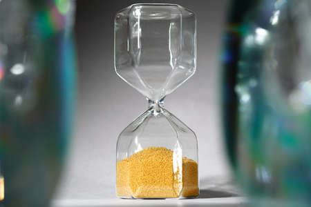 Hourglass with sand on gray background close up