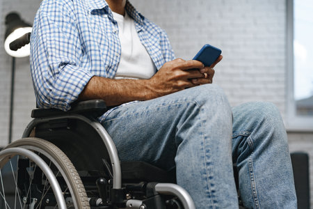 Mixed raced disabled man sitting in a wheelchair and using smartphoneの写真素材