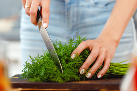 Woman cutting parsley on wooden board in kitchenの写真素材