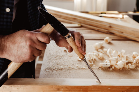 Hands of a carpenter working with chisel and hammerの写真素材