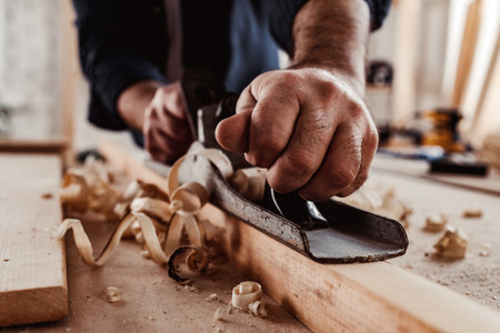 Carpenters hands planing a plank of wood with a hand plane