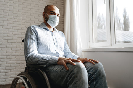 Disabled man sitting in a wheelchair and wearing face maskの写真素材