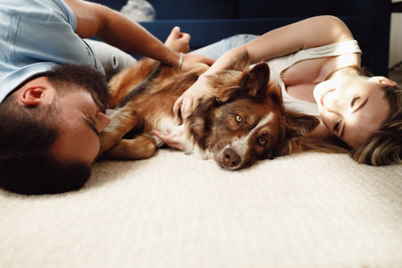 Happy couple lying on the floor with their dog, hugging with petの写真素材