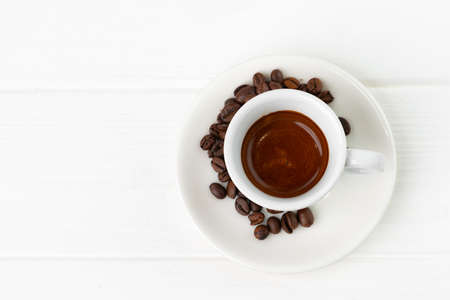 Cup of espresso coffee and coffee beans on white surfaceの写真素材