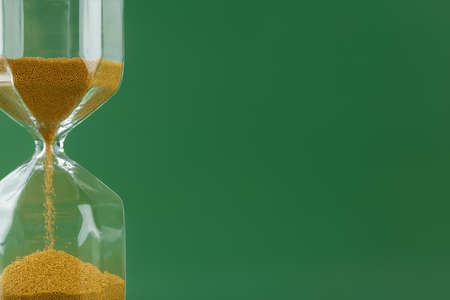 Gold hourglass on dark green paper background