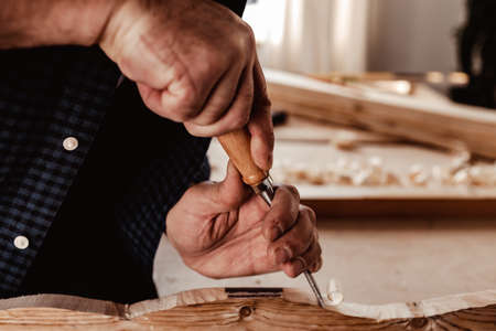 Hands of a carpenter working with chisel and hammer