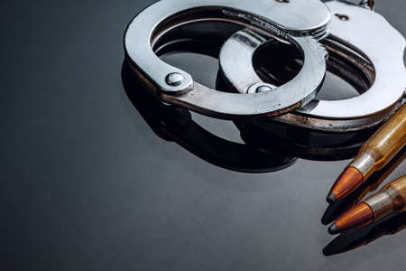 Handcuffs and rifle bullets on black background