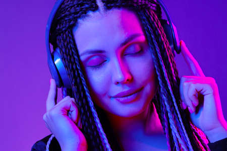 Beautiful woman with long hair in braids listening to music with headphones