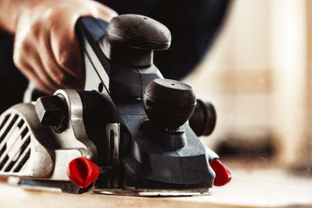 Carpenters hands working with electric planer in a workshopの写真素材