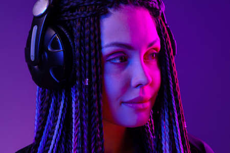 Beautiful woman with long hair in braids listening to music with headphonesの写真素材